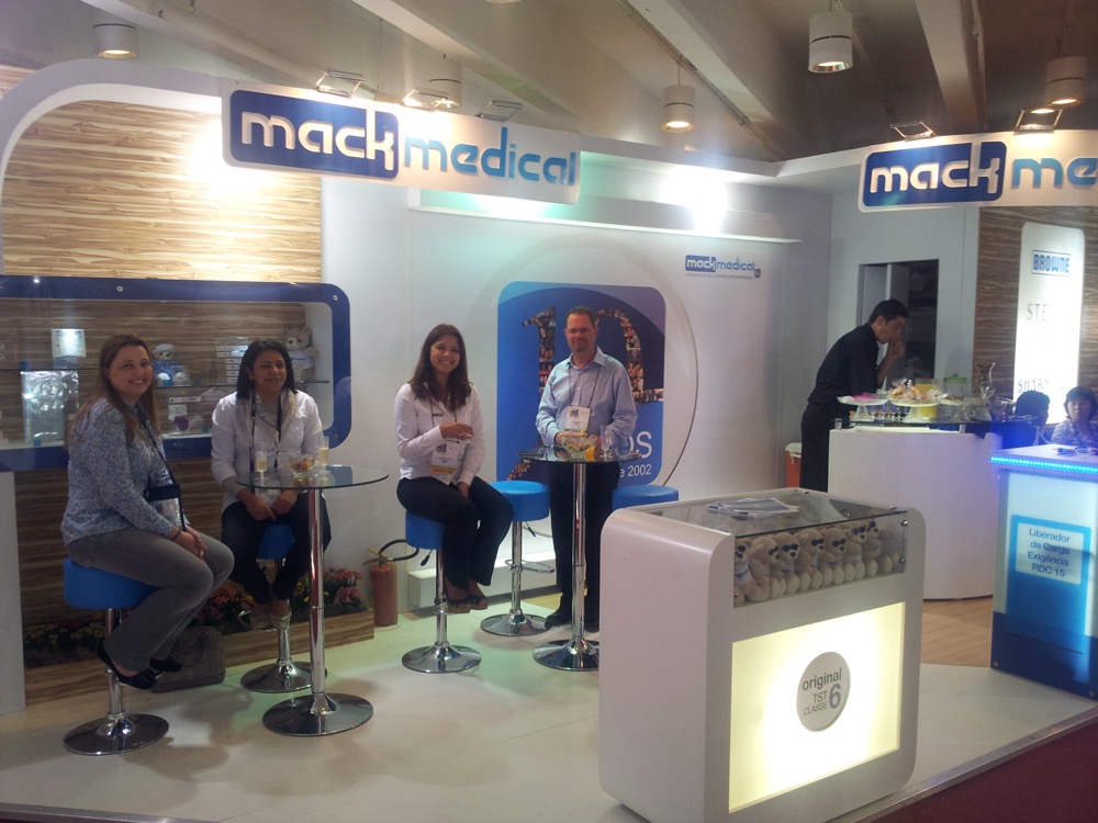 Equipe da Mack Medical no estande do congresso da SOBECC de 2012, com balcão de atendimento e painel da marca